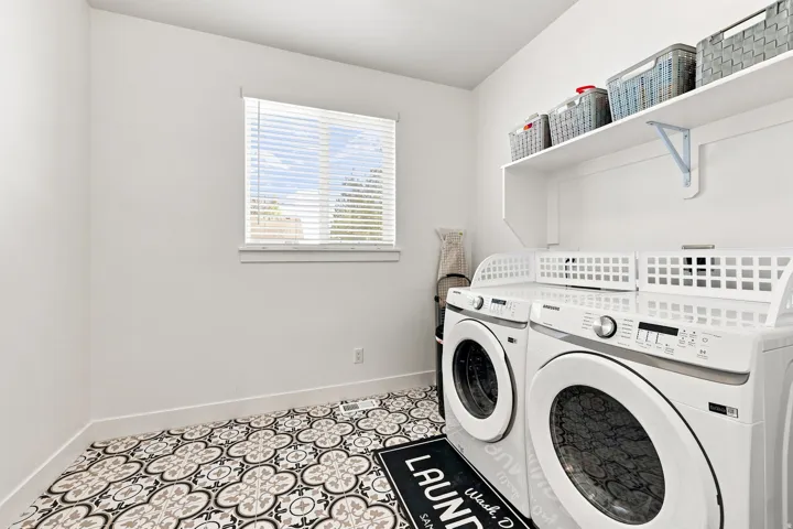 Patterned tile flooring, bright white walls, window with blinds, and an integrated shelf system