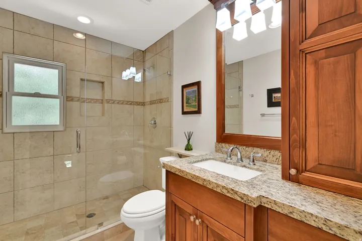 Tiled shower with a clear glass enclosure, integrated recessed niche, and a frosted window