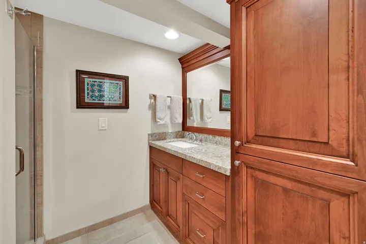 Wood-finish cabinetry with silver-tone hardware, a white undermount sink, and a light-toned countertop