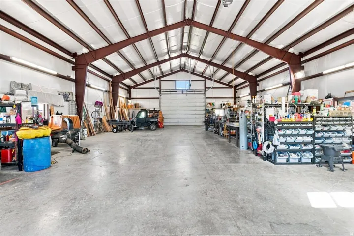 Spacious metal-frame garage with arched roof design, concrete flooring, and ample natural lighting from overhead panels
