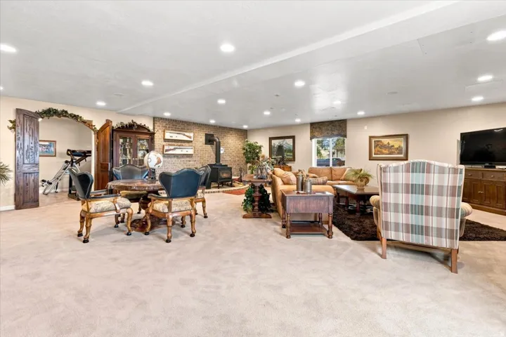 Spacious interior with recessed lighting, light-colored carpeting, a brick accent wall, and a built-in wood-burning stove