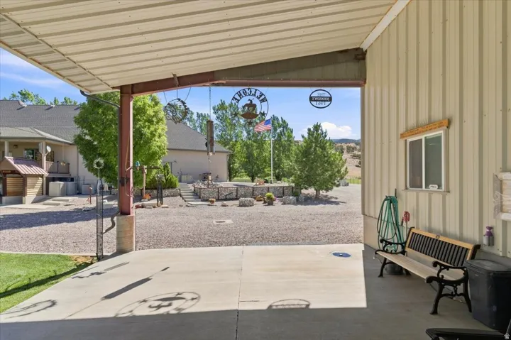 Shaded concrete patio with metal roof covering, corrugated metal siding, and a visible window