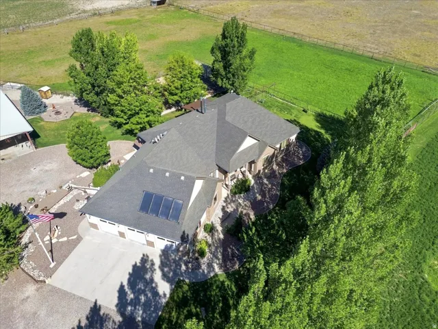 Shingle roof, attached multi-car garage, solar panels, expansive green spaces, and surrounding trees