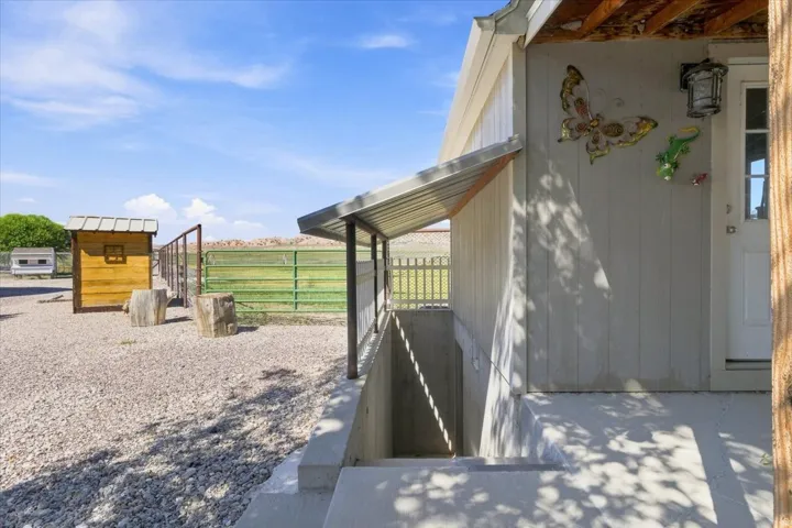 Gravel ground cover, exterior siding, concrete steps, metal awning, and a separate structure with a metal roof