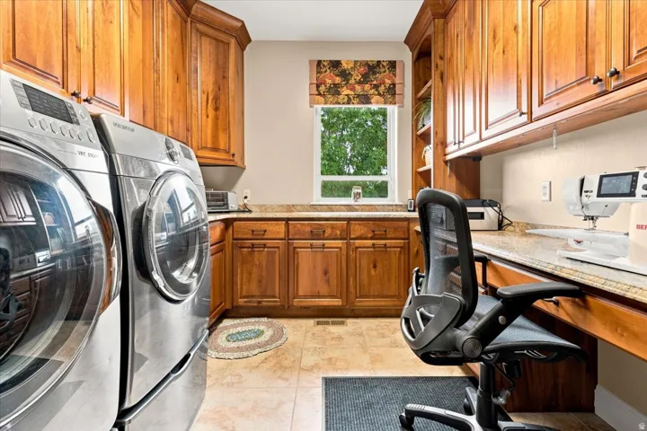 Laundry area with wood cabinetry, tile flooring, and integrated countertop space