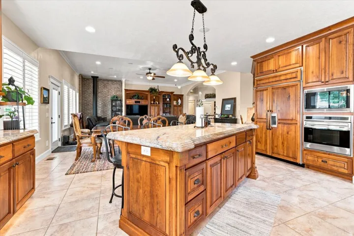 Kitchen featuring wood-finish cabinetry, a large center island with a light-toned countertop, and integrated stainless steel appliances