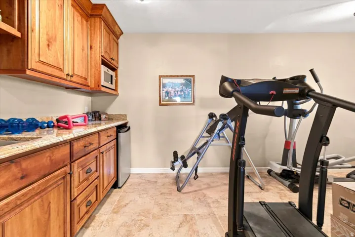 Built-in cabinetry with a stone-finish countertop, under-cabinet microwave, and compact refrigerator