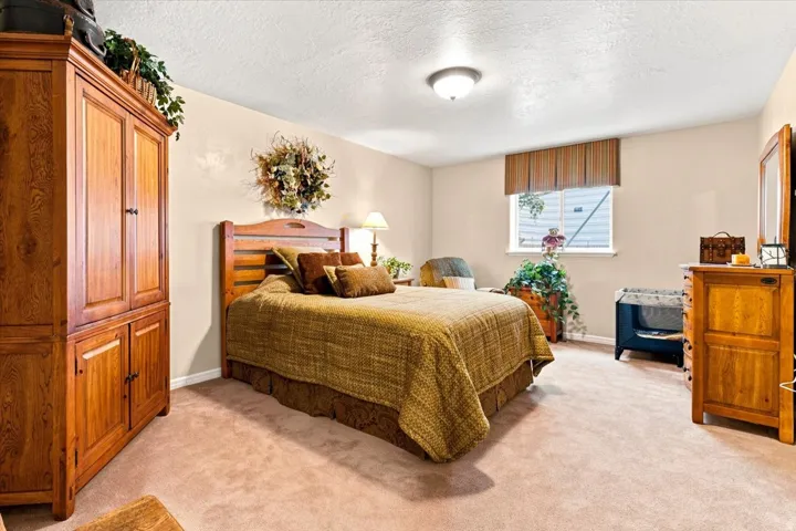 Soft neutral carpet flooring, a natural wood headboard, and a window with a striped valance