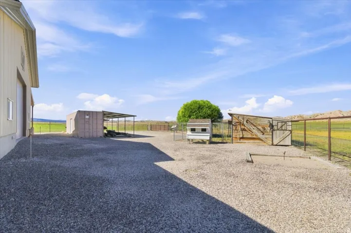 Gravel lot featuring a metal-sided barn, an additional outbuilding with a metal awning, and fenced enclosures