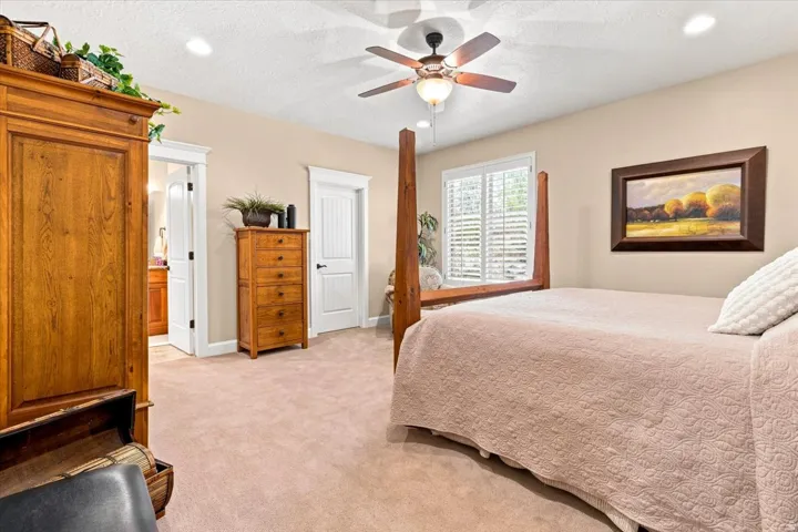 Recessed lighting, ceiling fan, carpeted flooring, window with plantation shutters, and a white paneled door