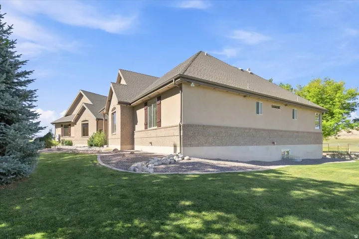 Expansive exterior featuring a stucco and brick facade, multiple gables, a shingled roof, and a mature evergreen tree
