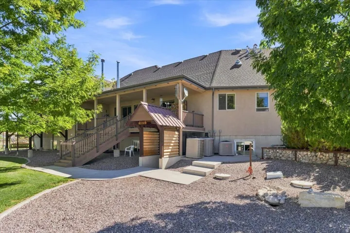 Expansive covered patio with wood-finish decking and railings, leading to a gravel and concrete-paved yard
