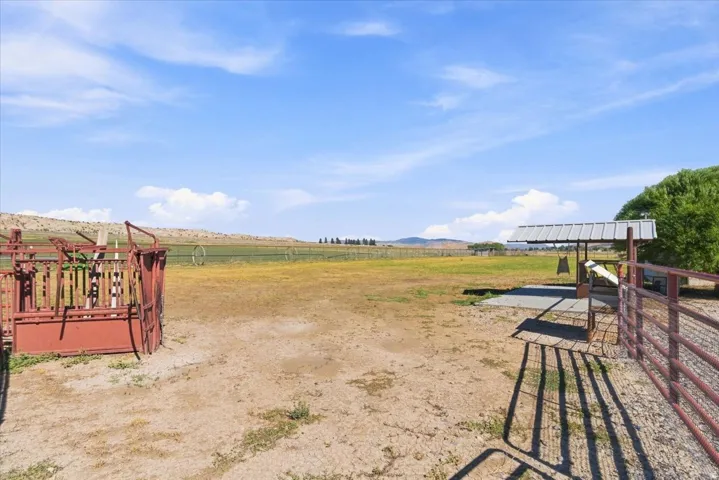 Expansive outdoor area featuring a metal-roofed shelter, red metal fencing, and distant green fields