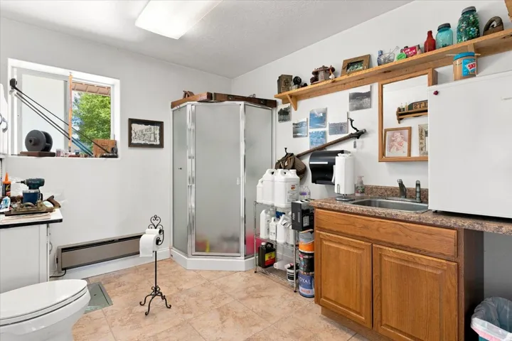 Three-piece bathroom featuring a corner shower, toilet, and vanity with an integrated sink