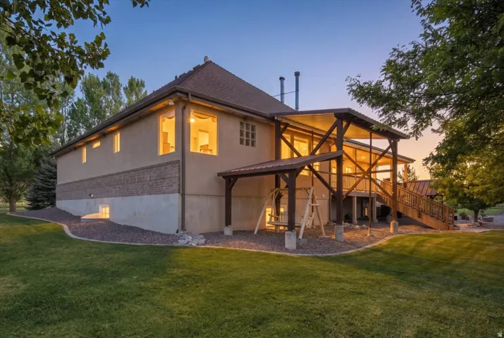 Expansive backyard with a manicured lawn, multi-level covered deck, and exterior wall featuring stone and stucco finishes