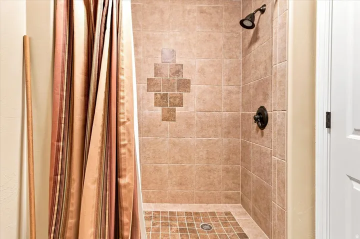 Tiled shower with a decorative mosaic accent, dark bronze shower head, and matching fixtures