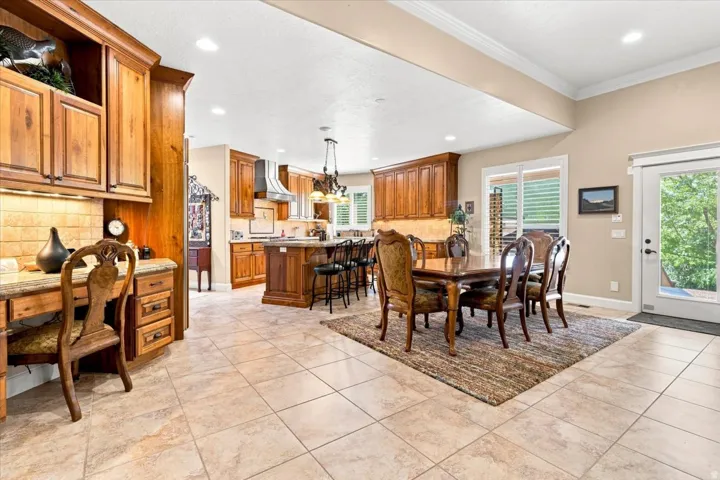 Open-concept kitchen and dining area featuring tile flooring, extensive wood cabinetry, a built-in desk, and a glass-paneled exterior door