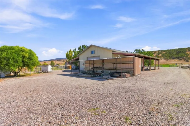Expansive gravel lot with a large building featuring a roll-up door and an extended covered awning