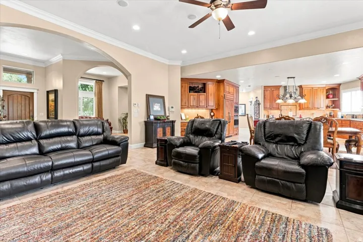 Arched architectural details frame a spacious living area featuring tile flooring, crown molding, and recessed lighting