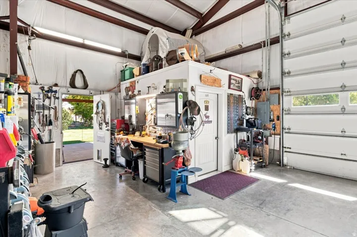Spacious garage featuring a concrete floor, high ceilings, large roll-up door, and an integrated workshop area