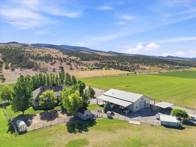 Expansive property featuring a residence, large workshop with covered overhangs, and additional storage structures