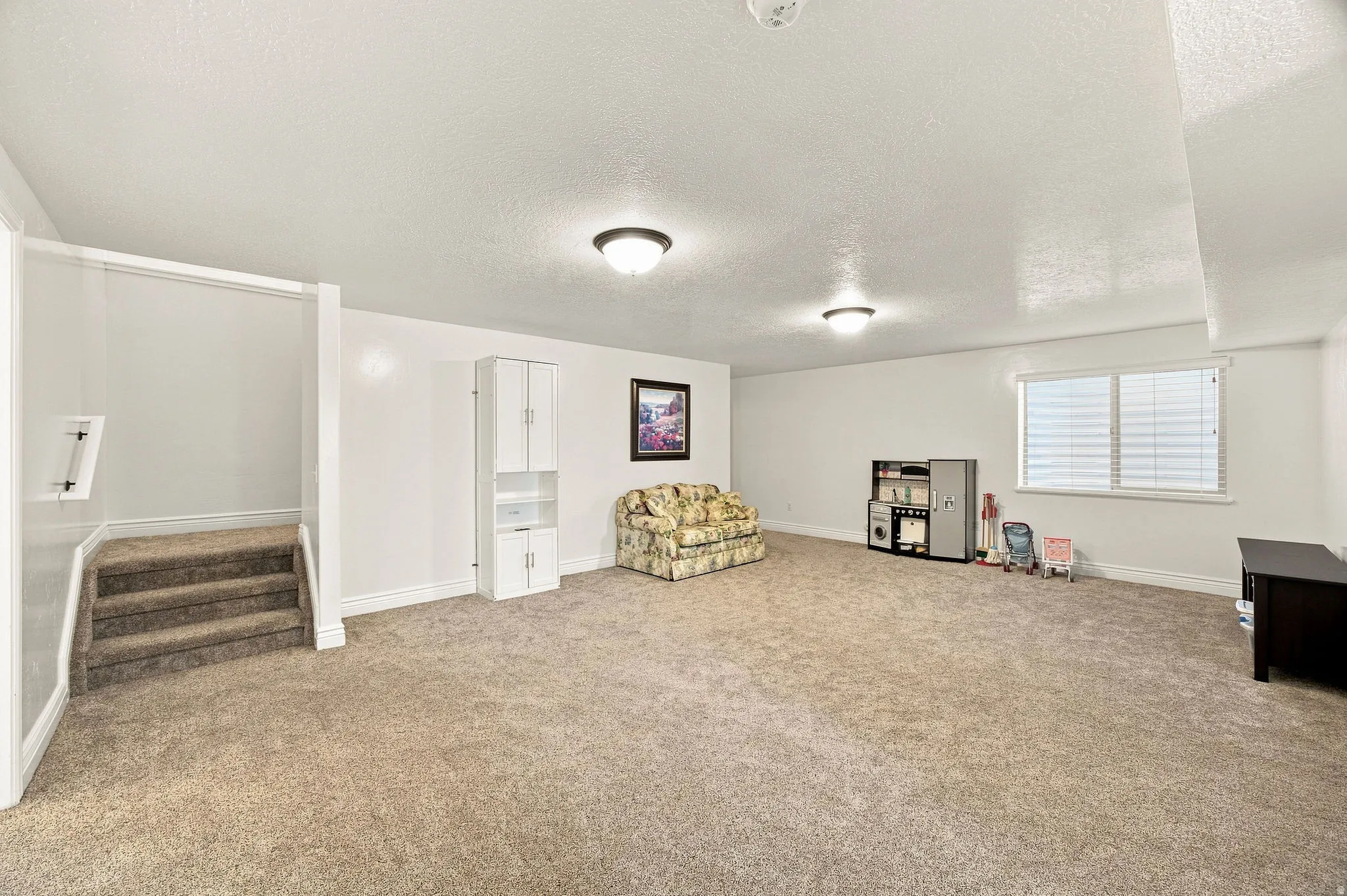 Spacious living room with carpet flooring, recessed window