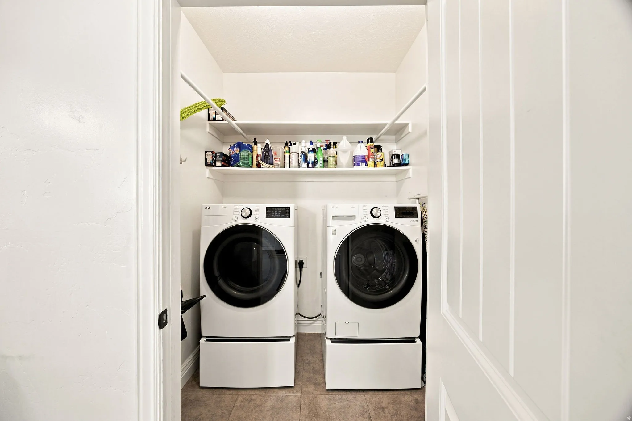 Laundry area featuring two built-in shelves and tile flooring