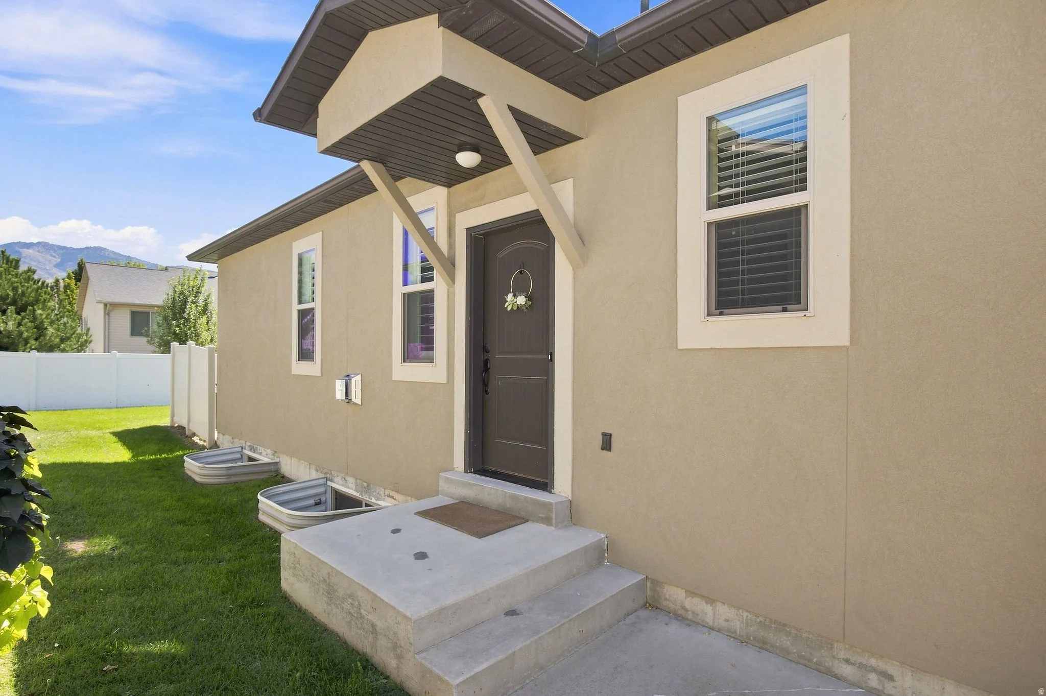 Stucco exterior with a covered entry and concrete steps