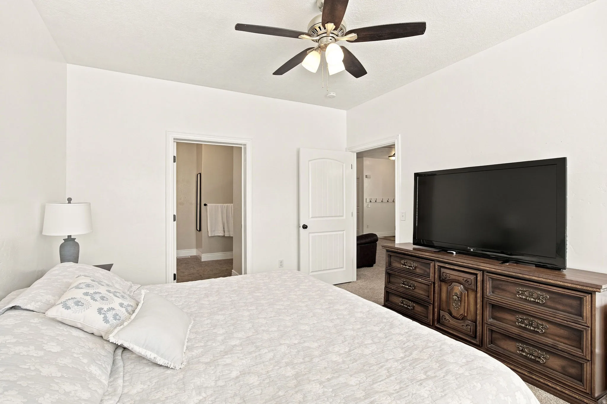 Vaulted ceiling with a ceiling fan, light-toned walls, and carpet flooring
