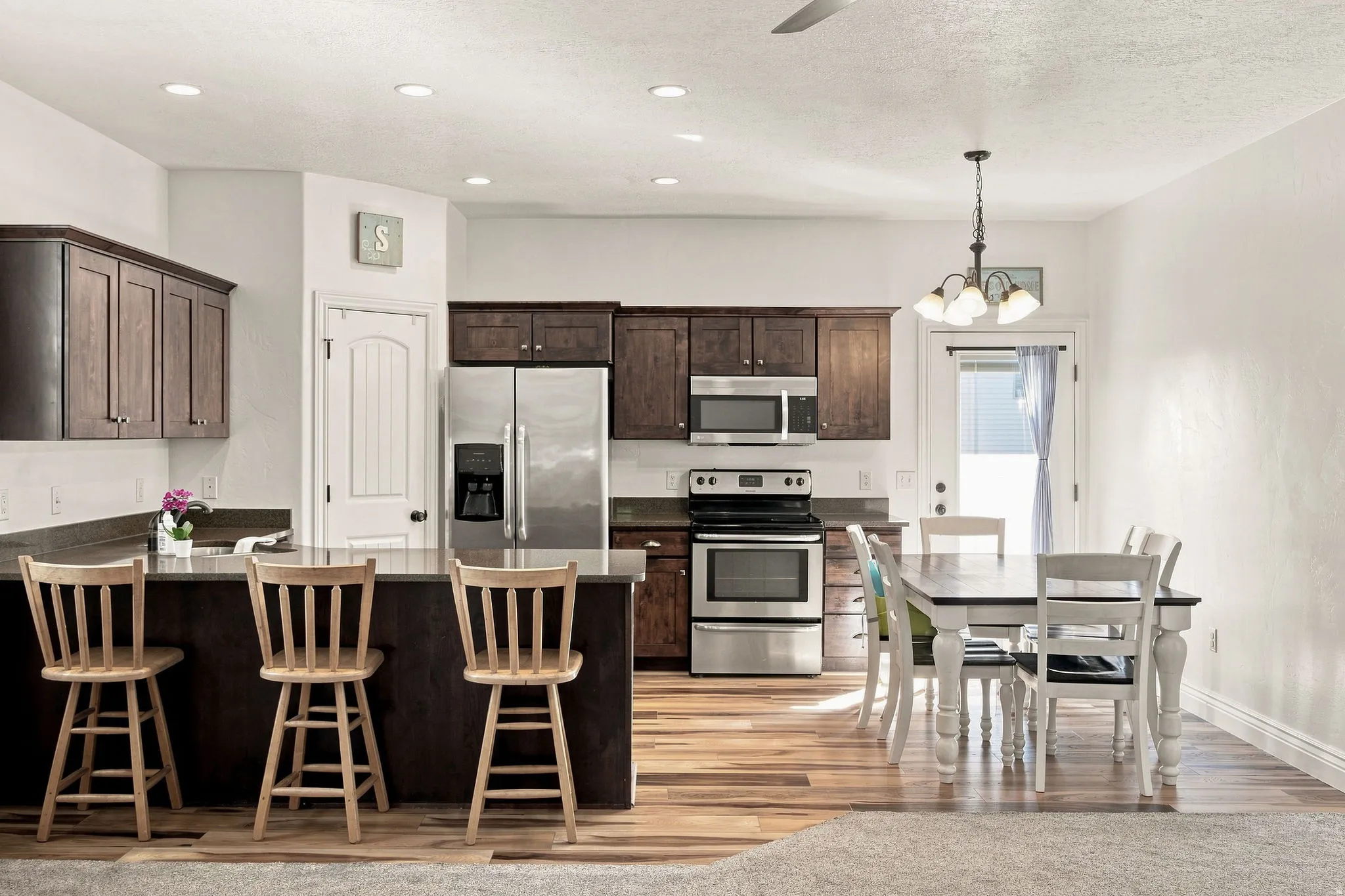 Kitchen featuring dark wood cabinetry, stainless steel appliances, a breakfast bar, and LVP flooring