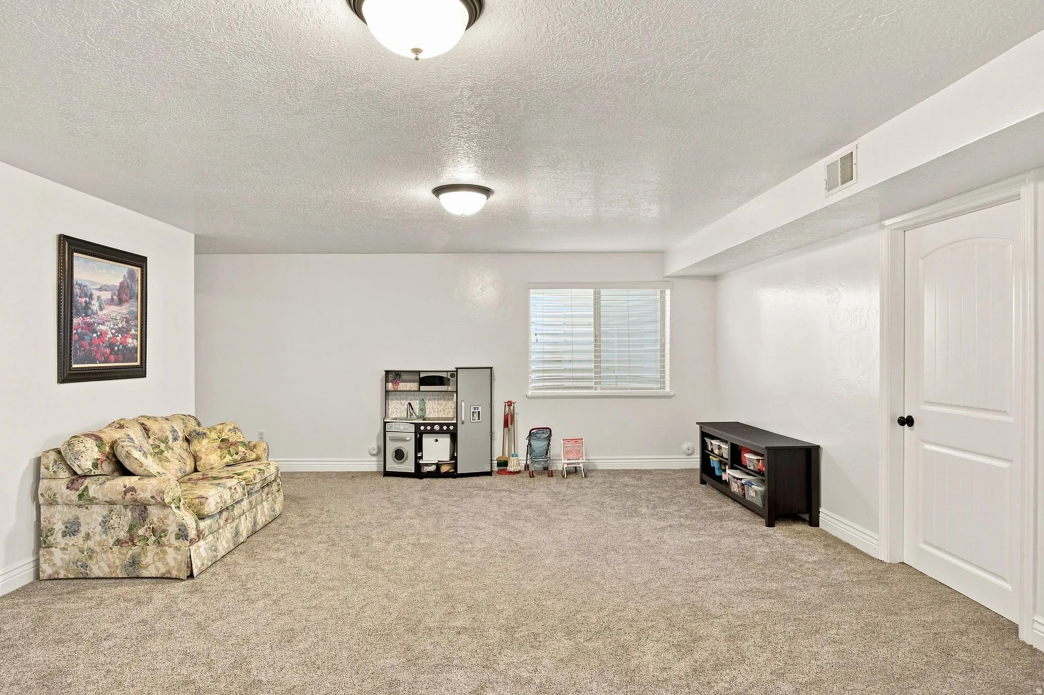Carpeted room featuring a window with blinds, white walls, and a white interior door