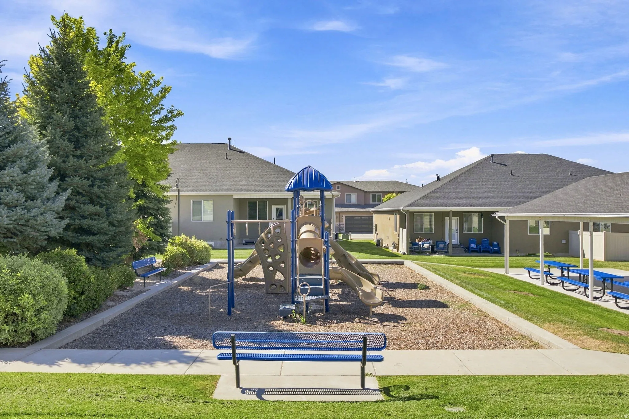 Recreational area featuring a playground structure, picnic tables, and shaded seating