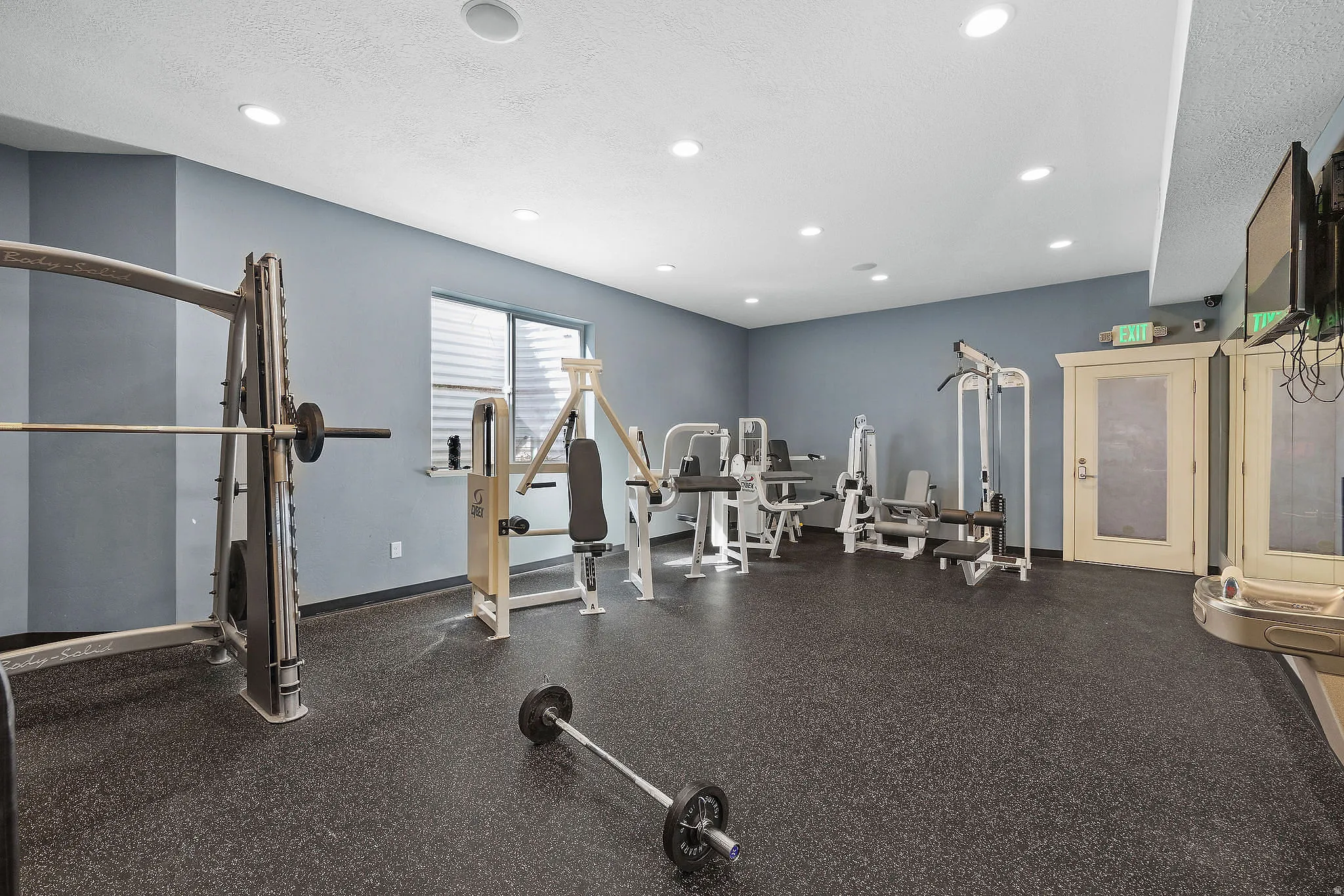 Weight fitness space featuring rubber flooring, recessed lighting, and a window with blinds
