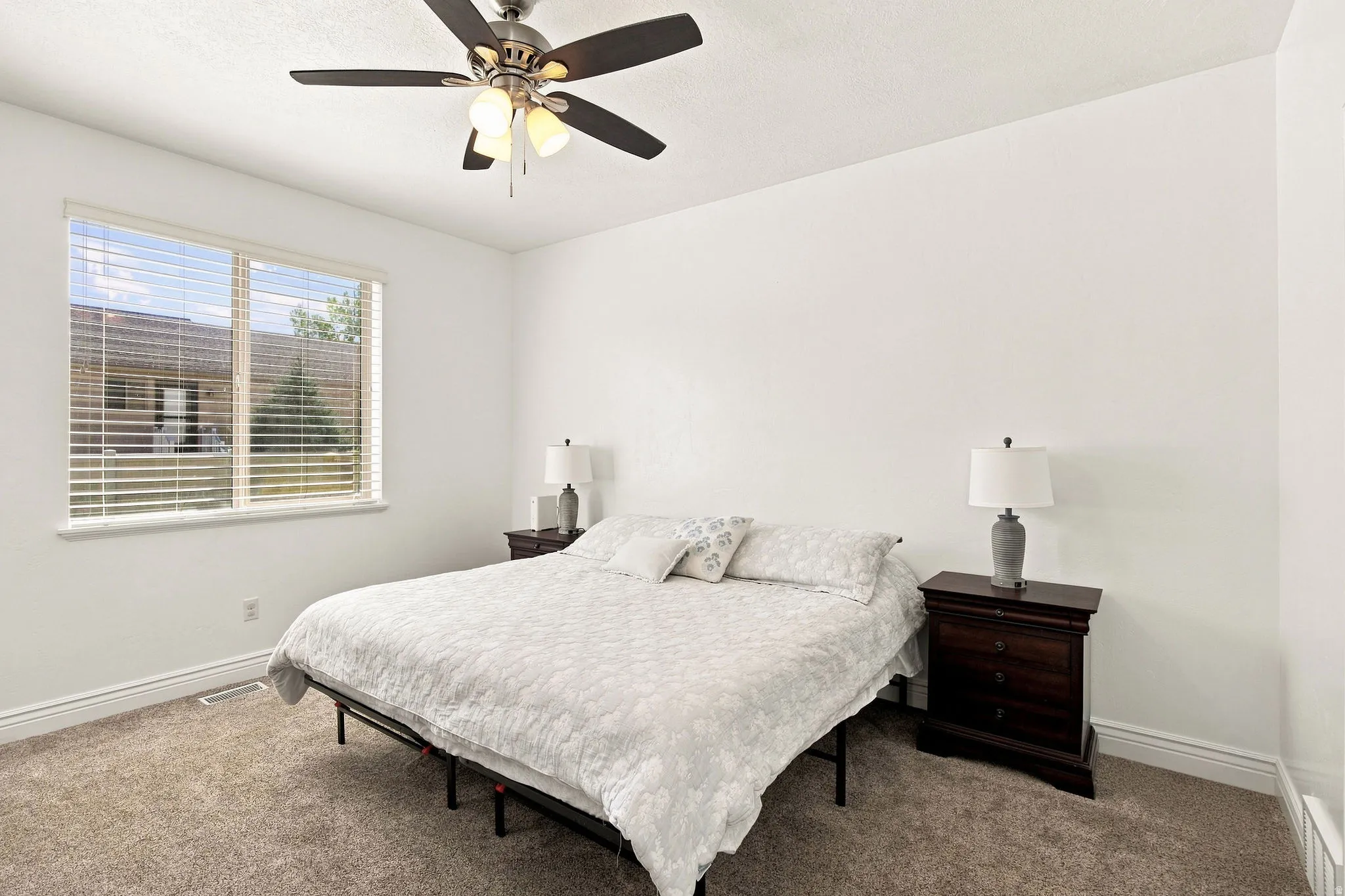 Primary bedroom featuring a ceiling fan with integrated lighting, carpet flooring, and window with horizontal blinds