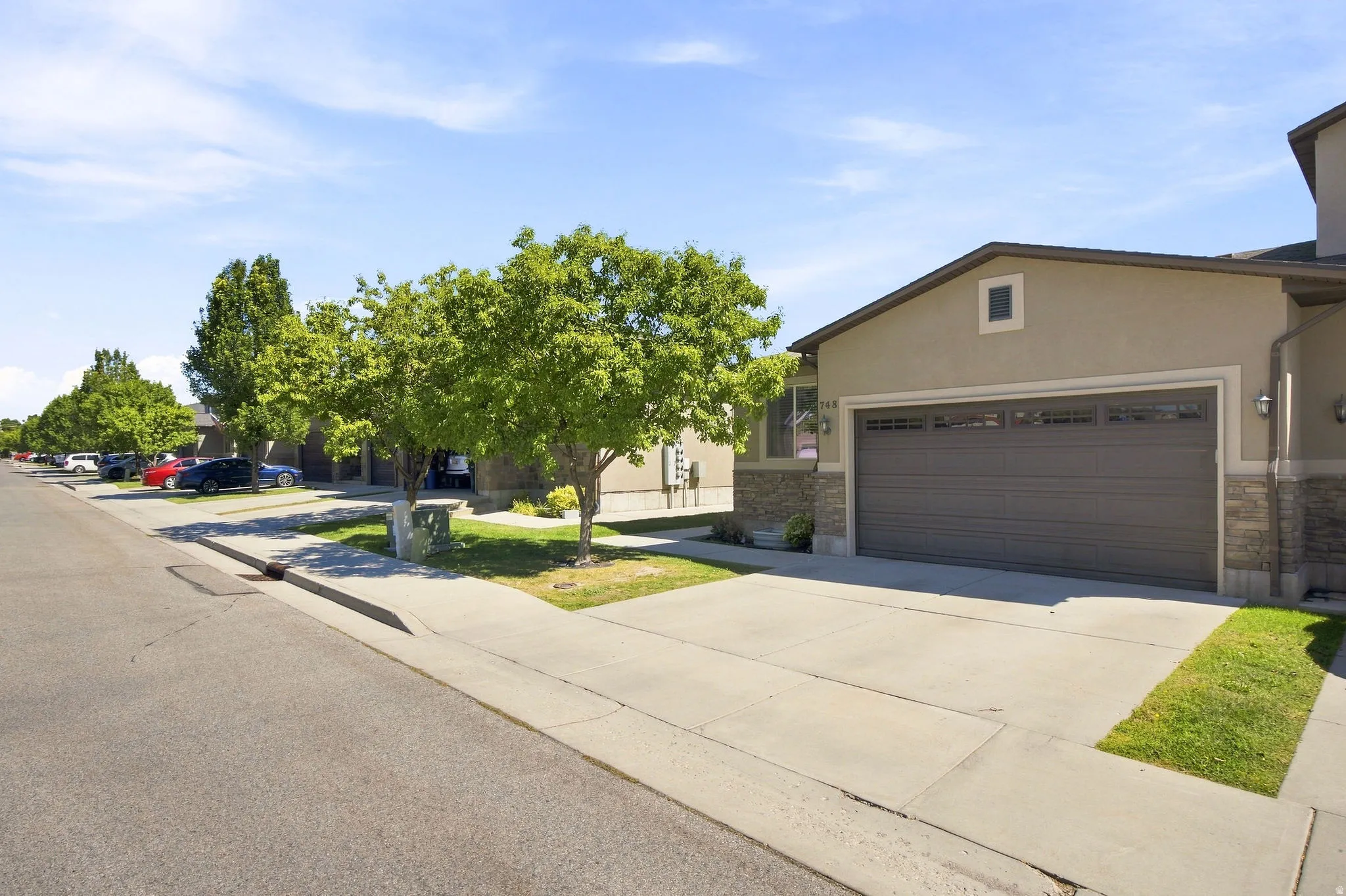 Stucco exterior with stone accents, an attached garage, and a concrete driveway
