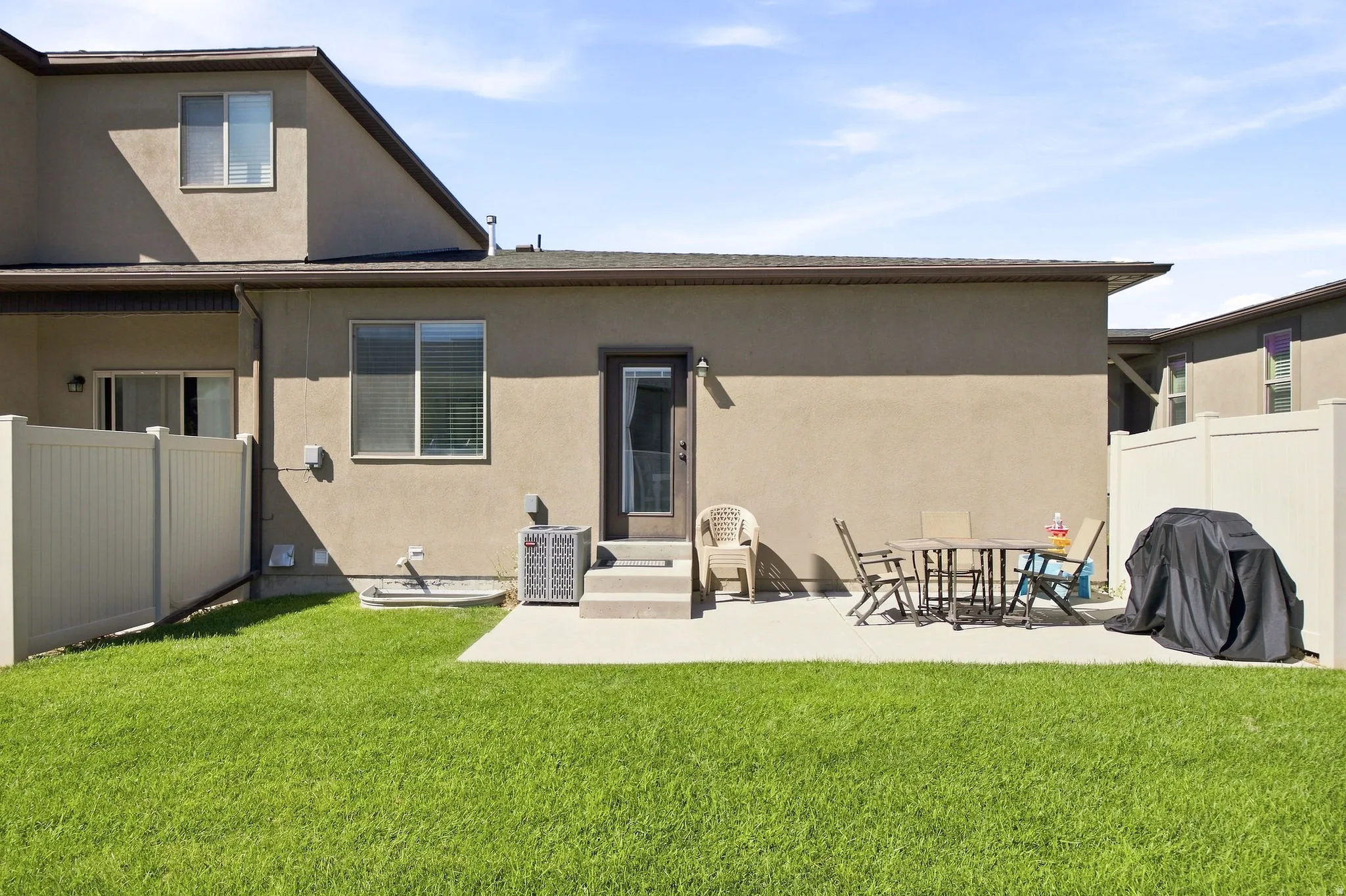 Expansive backyard featuring a concrete patio, privacy fencing, and a manicured lawn