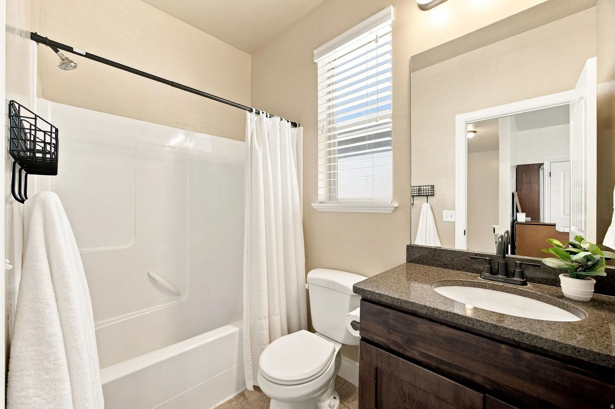 Bathroom featuring a built-in tub with shower, wood-finish vanity with granite countertop.