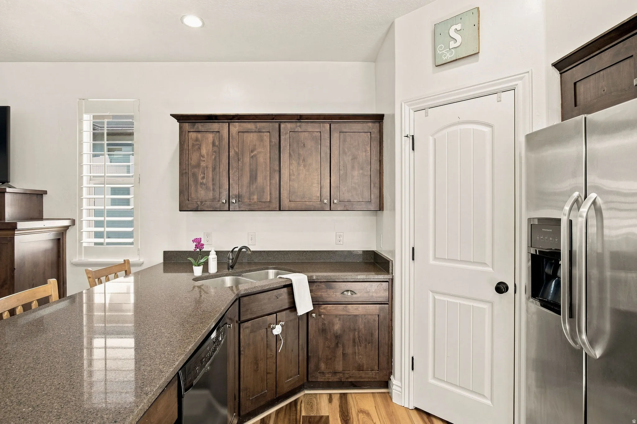 Kitchen featuring wood-finish flooring, dark wood cabinetry, a double basin sink with a gooseneck faucet, and stainless steel appliances