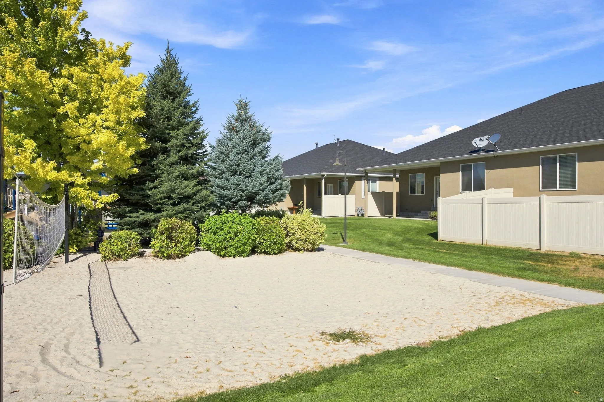 Sand volleyball court with lush surrounding landscaping and a manicured lawn