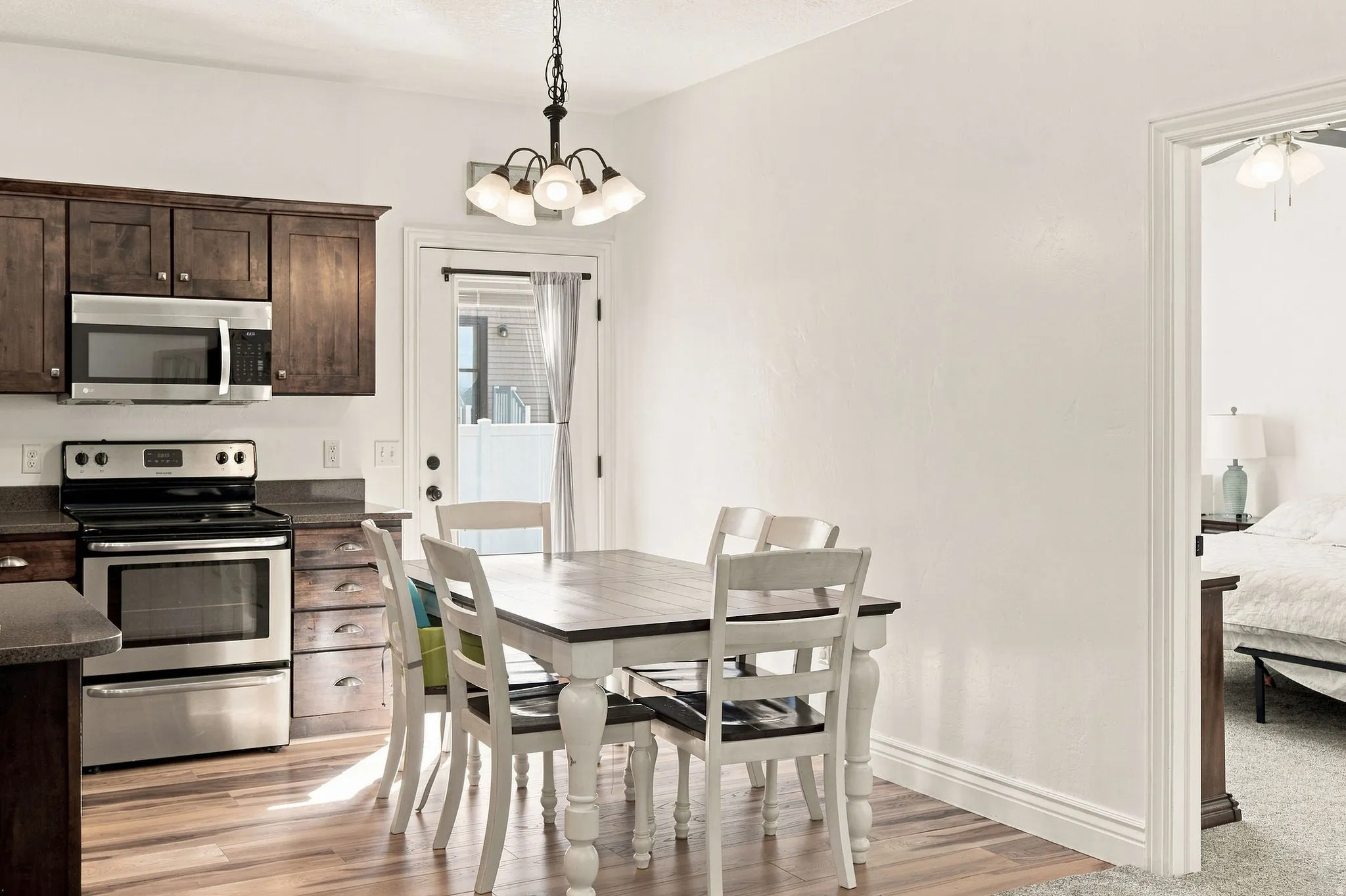 Kitchen featuring wood-finish flooring, stainless steel appliances, dark wood cabinetry, and a ceiling-mounted chandelier