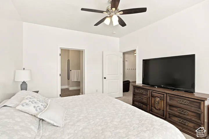 Vaulted ceiling with a ceiling fan, light-toned walls, and carpet flooring