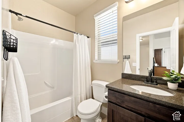 Bathroom featuring a built-in tub with shower, wood-finish vanity with granite countertop.