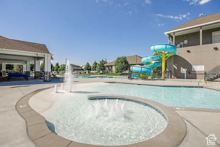 Expansive pool area featuring a water slide, multiple water features, and a covered pavilion