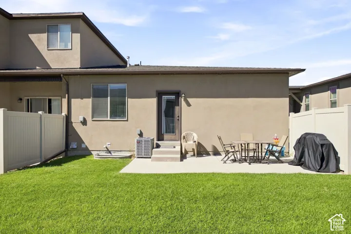 Expansive backyard featuring a concrete patio, privacy fencing, and a manicured lawn