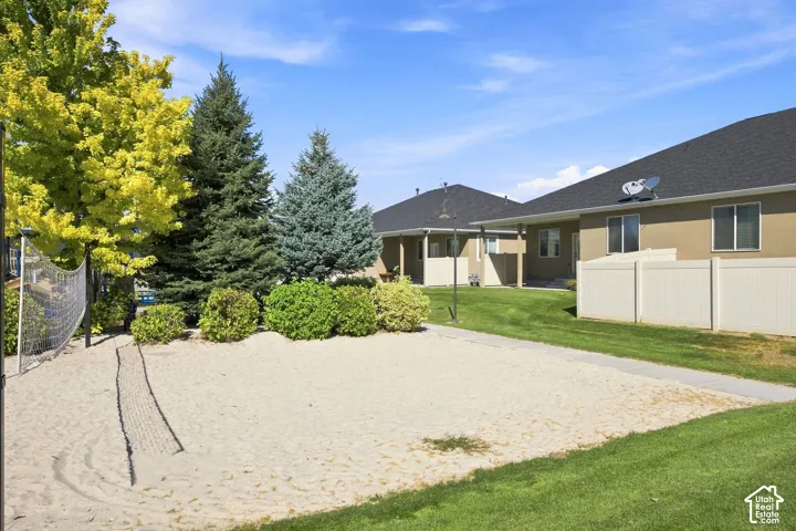 Sand volleyball court with lush surrounding landscaping and a manicured lawn