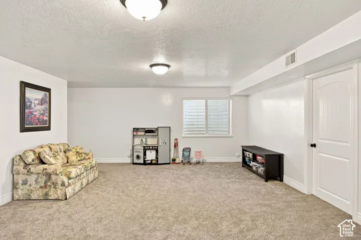 Carpeted room featuring a window with blinds, white walls, and a white interior door