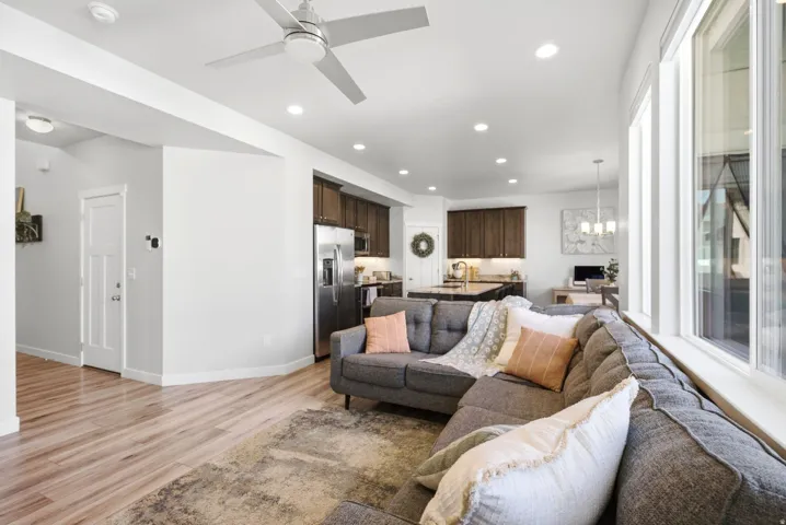 Open-concept living space with wood-finish flooring, a contemporary ceiling fan, recessed lighting, and a kitchen featuring dark wood cabinetry and stainless steel appliances
