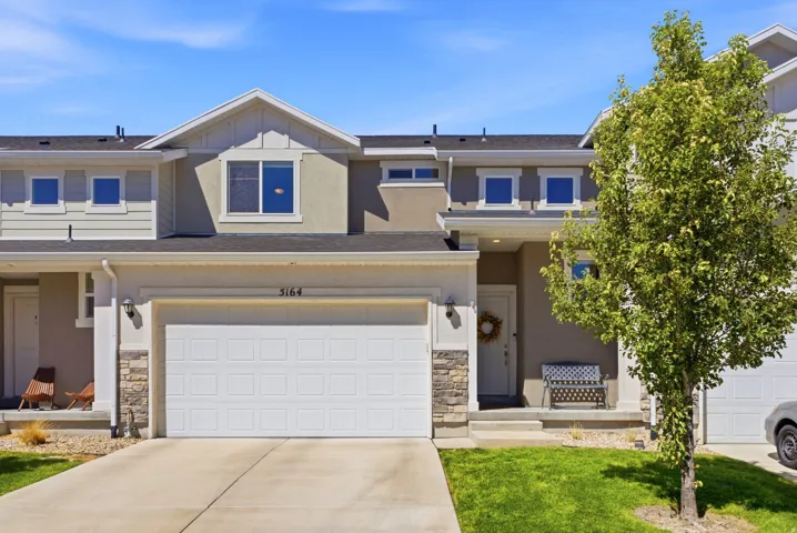 Two-story exterior with a panel garage door, stone accent columns, and a covered entry