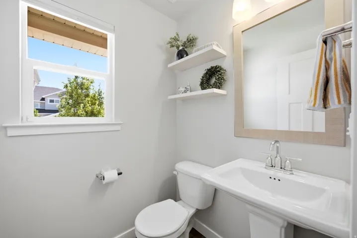 Pedestal sink with chrome faucet, framed mirror, and two floating shelves