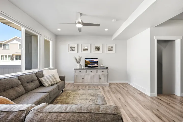 Spacious living area featuring large windows, wood-finish flooring, recessed lighting, and a ceiling fan